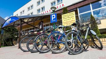 A hotel with a covered entrance, a parking sign, and bicycles parked outside.