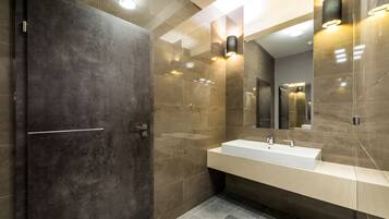 Une salle de bain moderne avec un grand miroir, un lavabo et une porte.