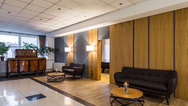 A modern lobby with a wooden reception desk, two sofas, and a coffee table. - Hotel Wodnik (Gizycko)