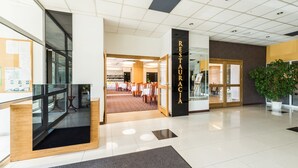 A modern hotel lobby with a reception desk, a staircase, and a restaurant area. - Hotel Wodnik (Gizycko)
