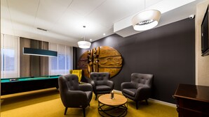 A modern lounge with a pool table, leather armchairs, a round coffee table, and a large abstract wall art piece. - Hotel Wodnik (Gizycko)
