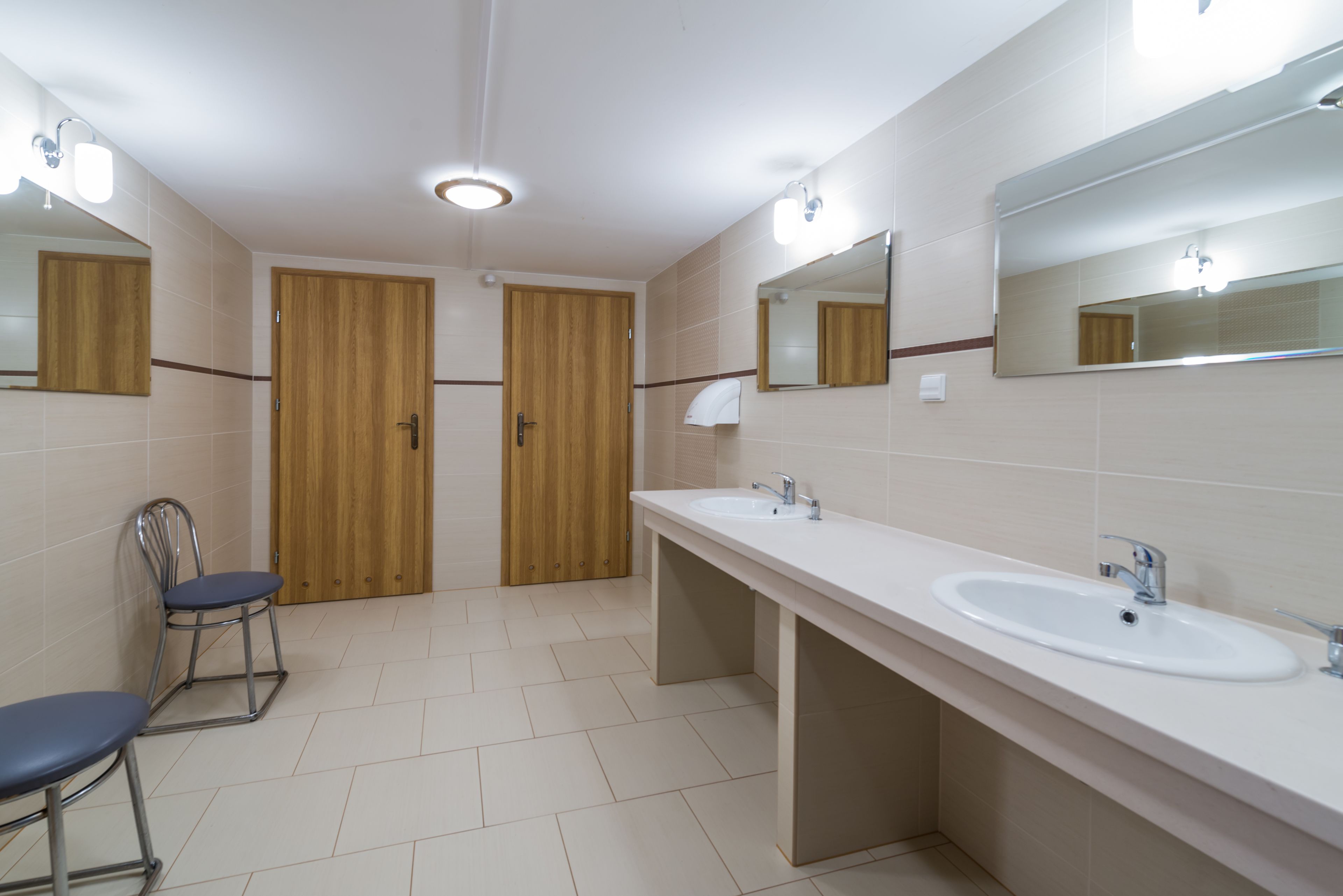 A modern bathroom with two sinks, a mirror, and a chair.