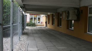 A corridor with a tiled floor, metal fence, and a building entrance with a sign.