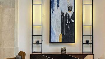 Una sala de estar moderna con un cuadro abstracto grande, un sofá, una mesa de centro y un sillón marrón.