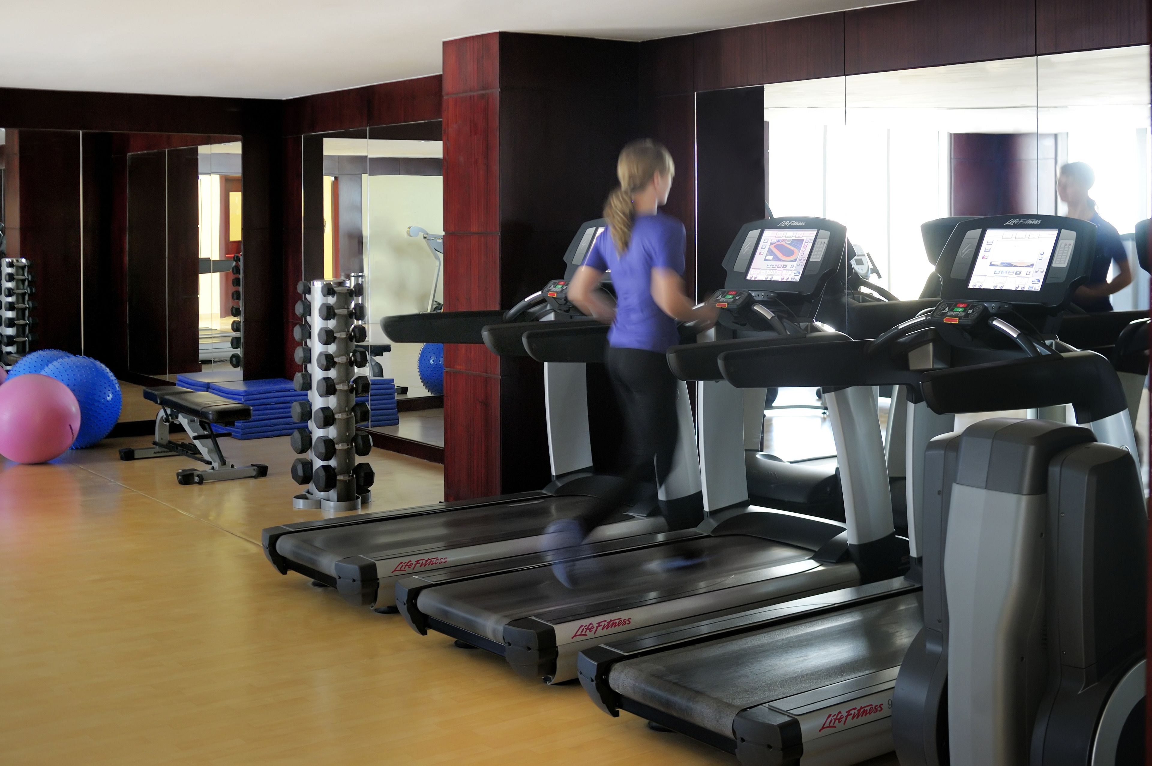 Un gimnasio con cintas de correr, pelotas de ejercicio y máquinas de pesas.