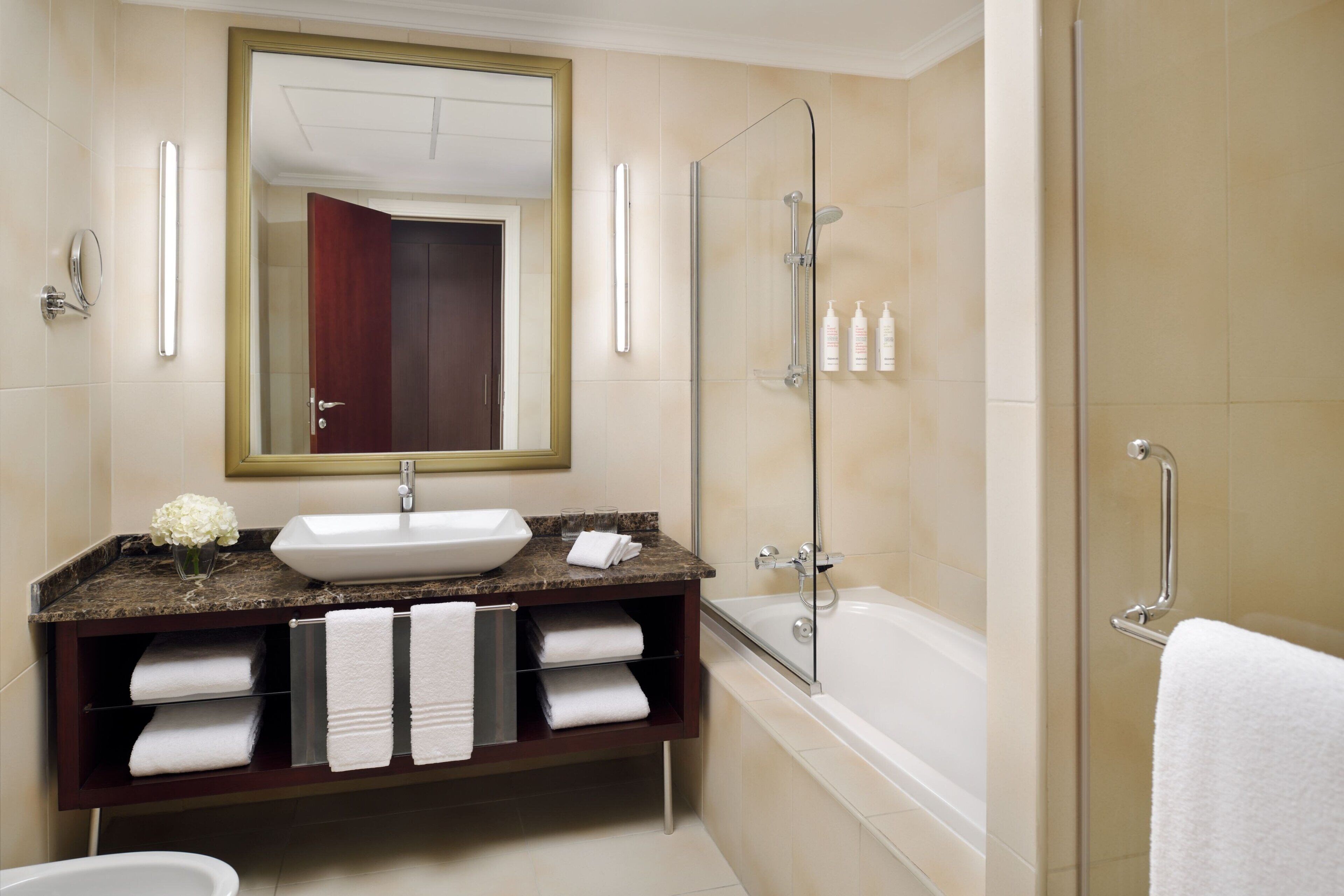 A modern bathroom with a large sink, vanity, and a walk-in shower.