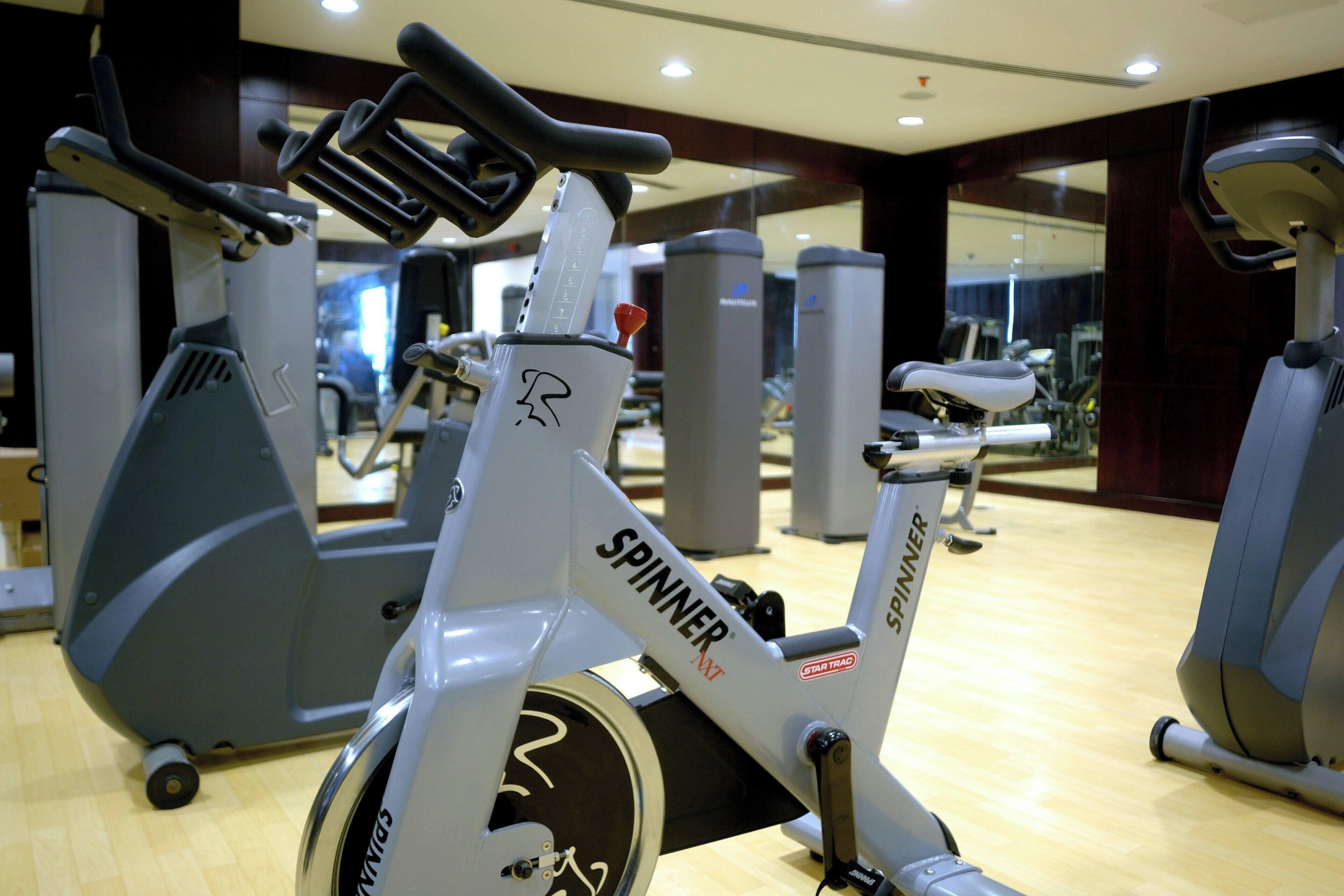 A gym with stationary bikes labeled 'SPINNER' and 'STARTRAC'.