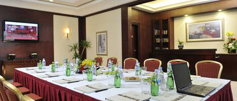 A conference room with a long table, chairs, a laptop, water bottles, and a television on the wall.