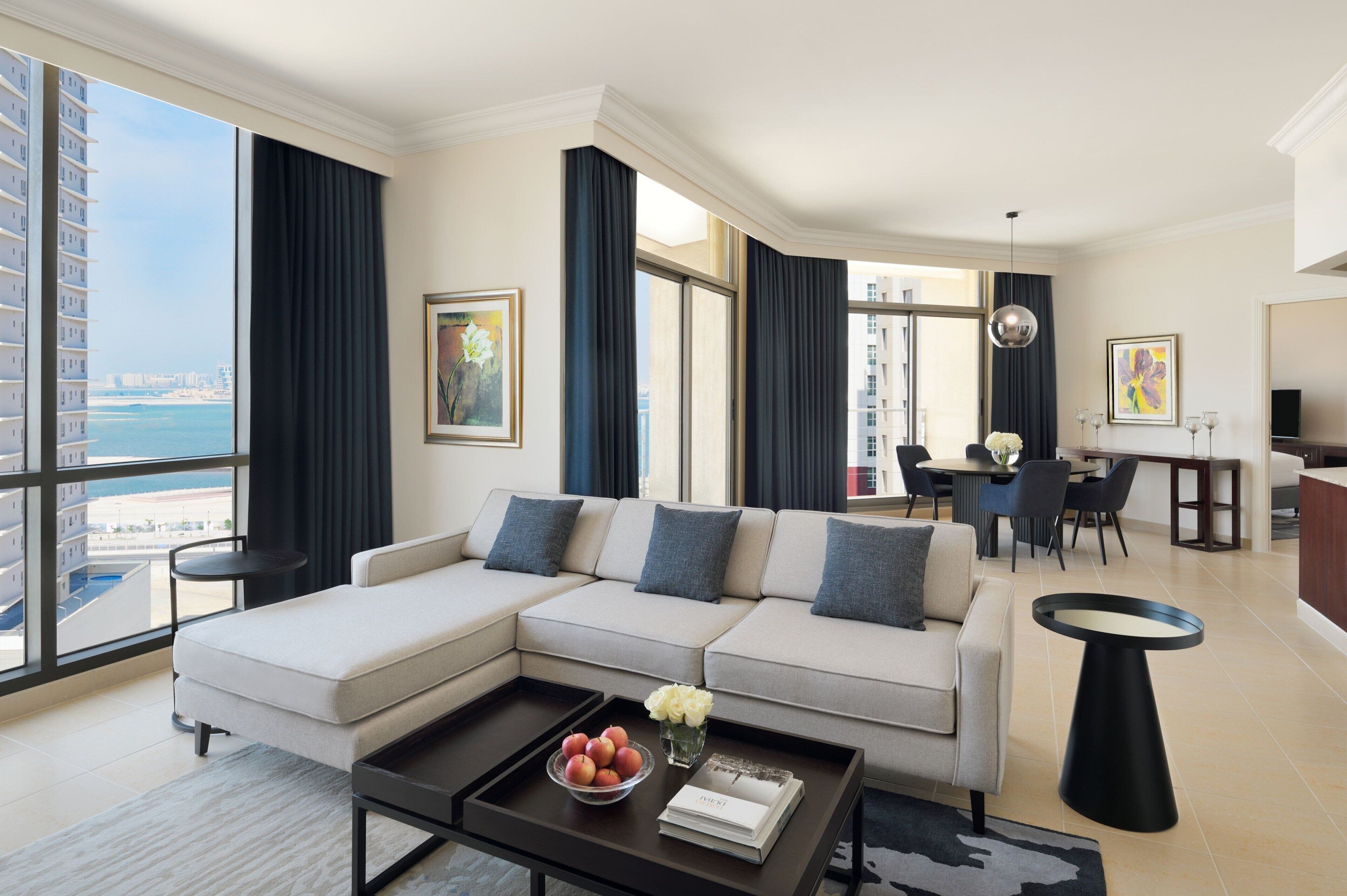 Un salon moderne doté d’un grand canapé, d’un coin repas et offrant une vue sur la ville.