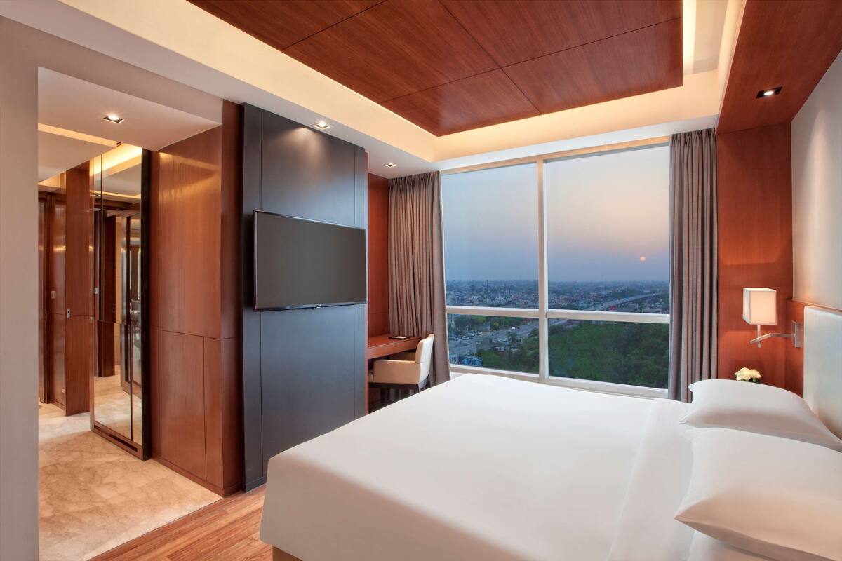 A modern hotel room with a large bed, a desk, and a TV.