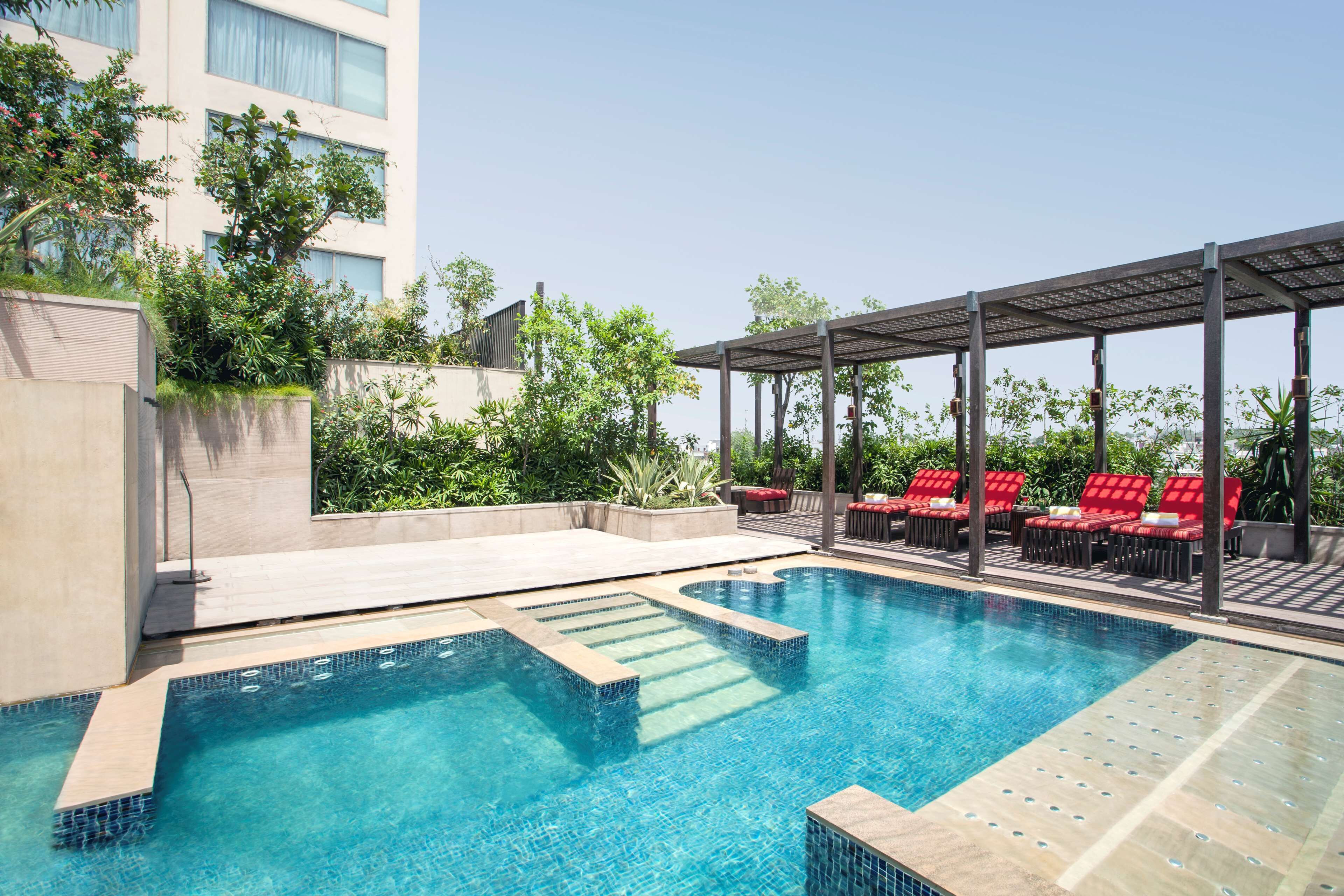 A swimming pool with red lounge chairs and a covered seating area.