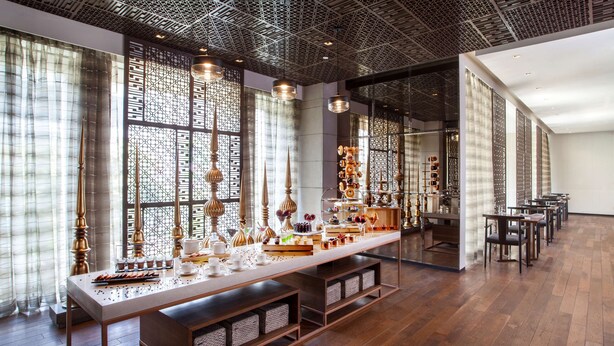 A spacious room with a long table displaying various food items, a patterned ceiling, and large windows with curtains. - Hyatt Regency Amritsar Hotel & Spa (Amritsar)