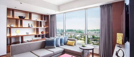 Un salón moderno con un sofá modular, estanterías de madera y un amplio ventanal con vistas a la ciudad.