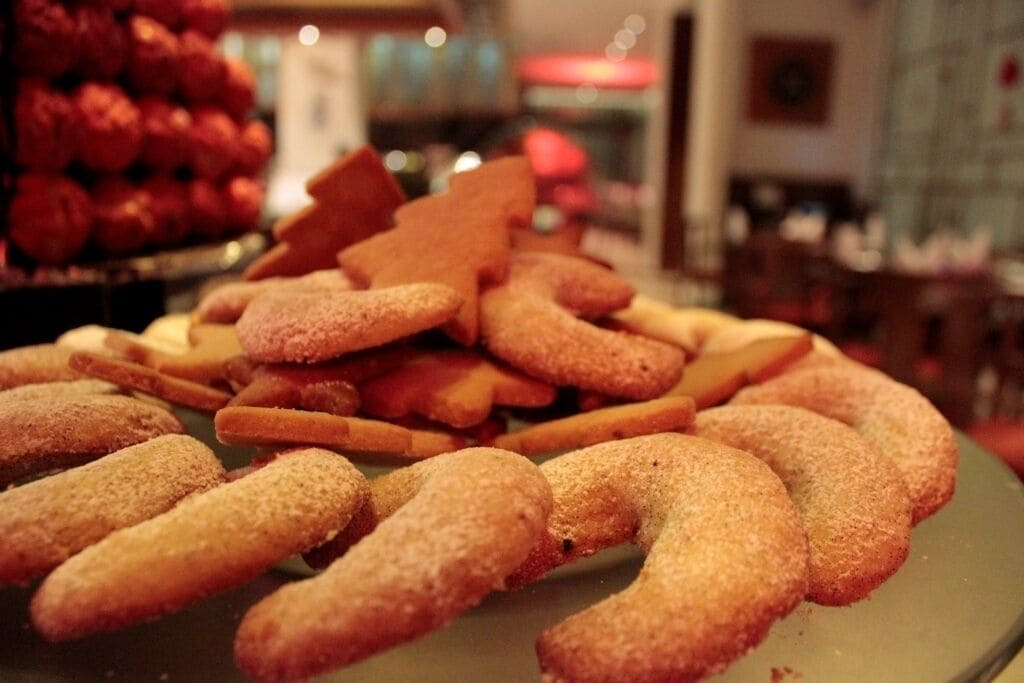 A plate of assorted cookies and pastries, including sugar-dusted pretzels and other shapes, in a dining setting.