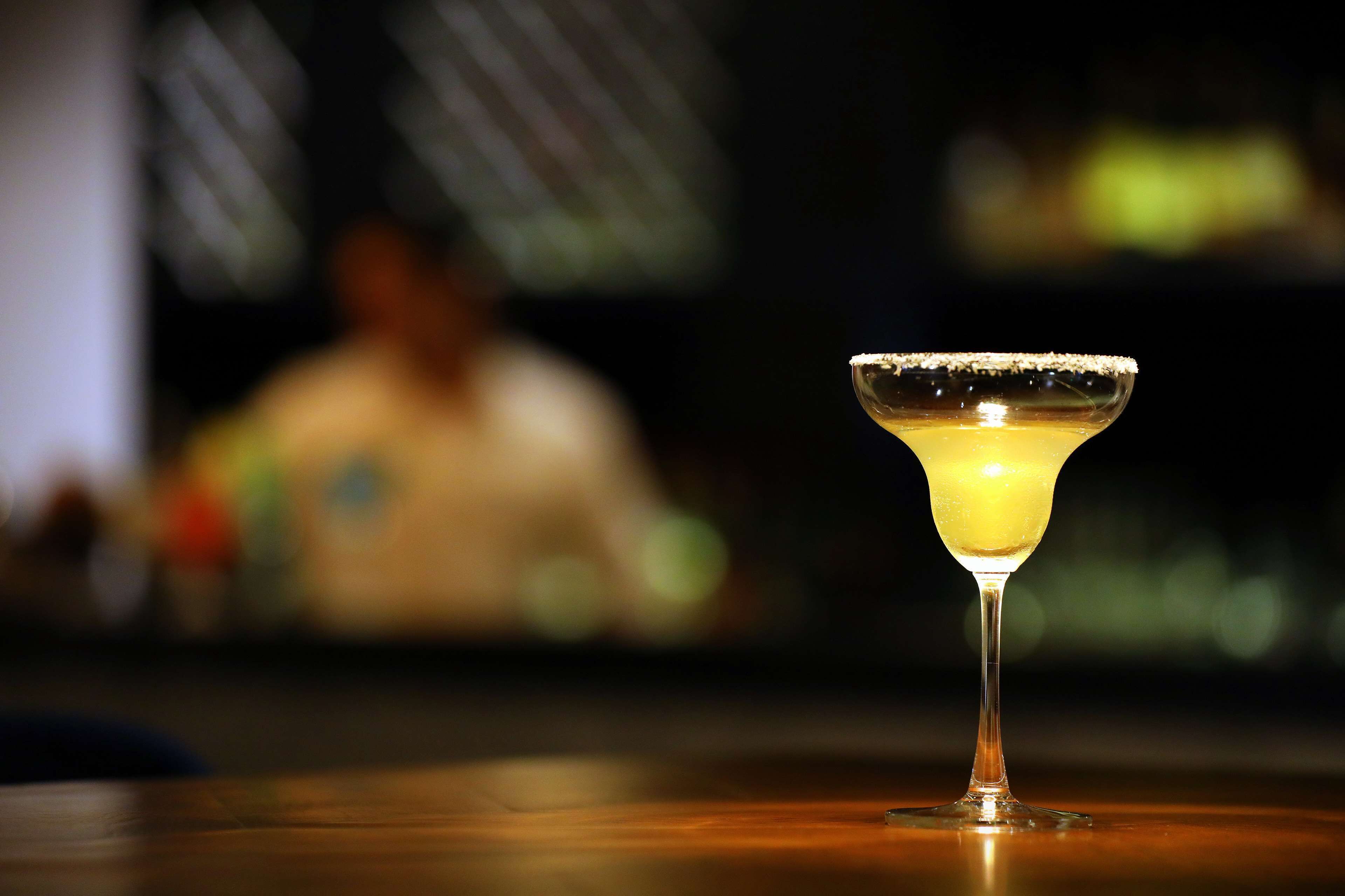 A cocktail in a martini glass with a salted rim on a wooden table.