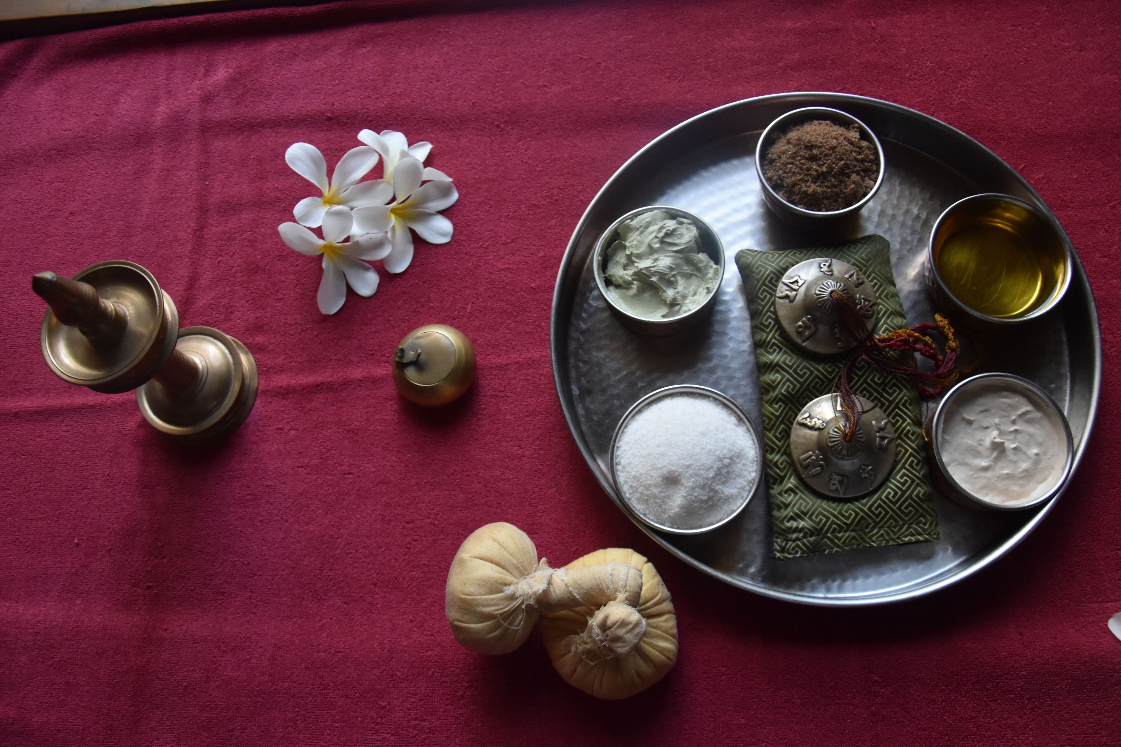 A tray with various items including a flower, a metal cup, and containers of different substances.