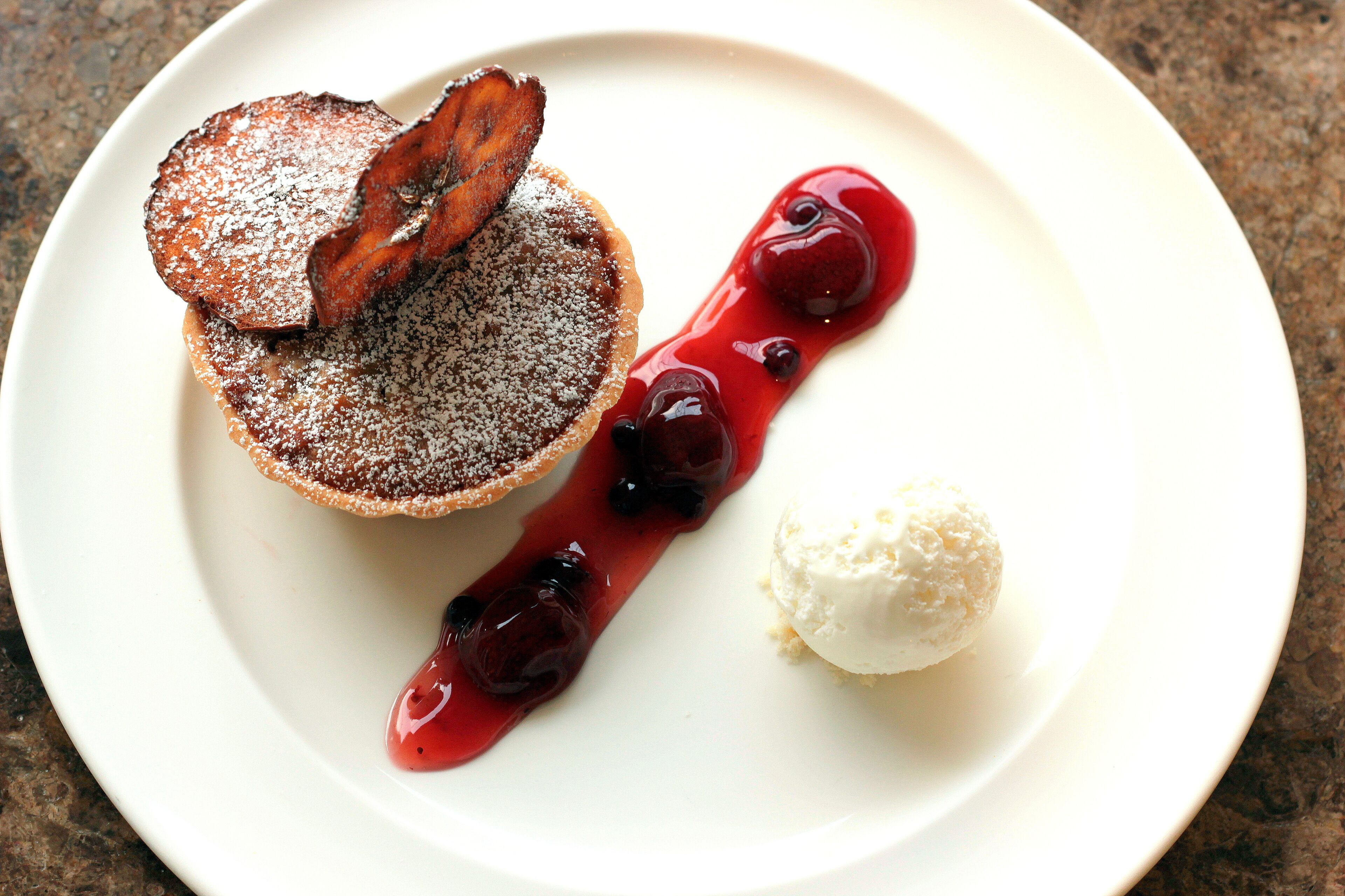 A dessert plate with a slice of cake, cherries, and a scoop of ice cream.