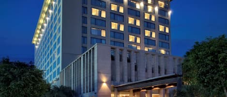 A modern hotel with a prominent entrance, multiple floors, and illuminated windows.