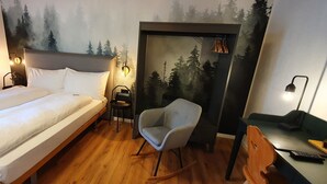 A hotel room with a bed, a desk, a chair, and a wall mural. - Schorta's Hotel Alvetern (Scuol)