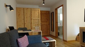 A cozy room with a wooden wardrobe, a desk with a laptop, a sofa with cushions, and a small table. - Schorta's Hotel Alvetern (Scuol)