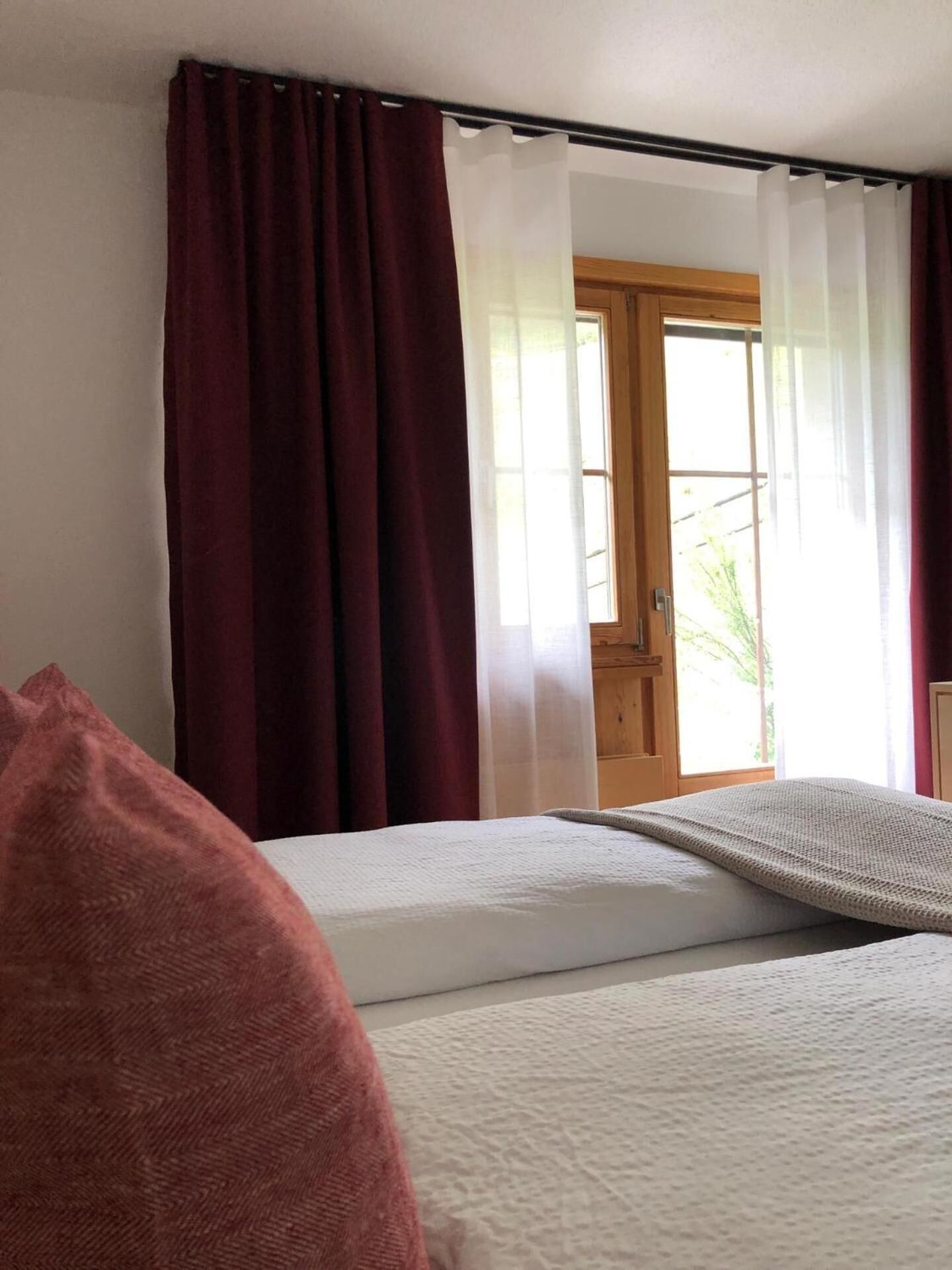 Un dormitorio con una cama, una ventana con cortinas y una puerta que da al exterior.