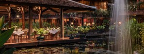A restaurant with outdoor seating, a pond with lily pads, and a waterfall. - Angkor Village Hotel - Small Luxury Hotels of the World (Siem Reap)