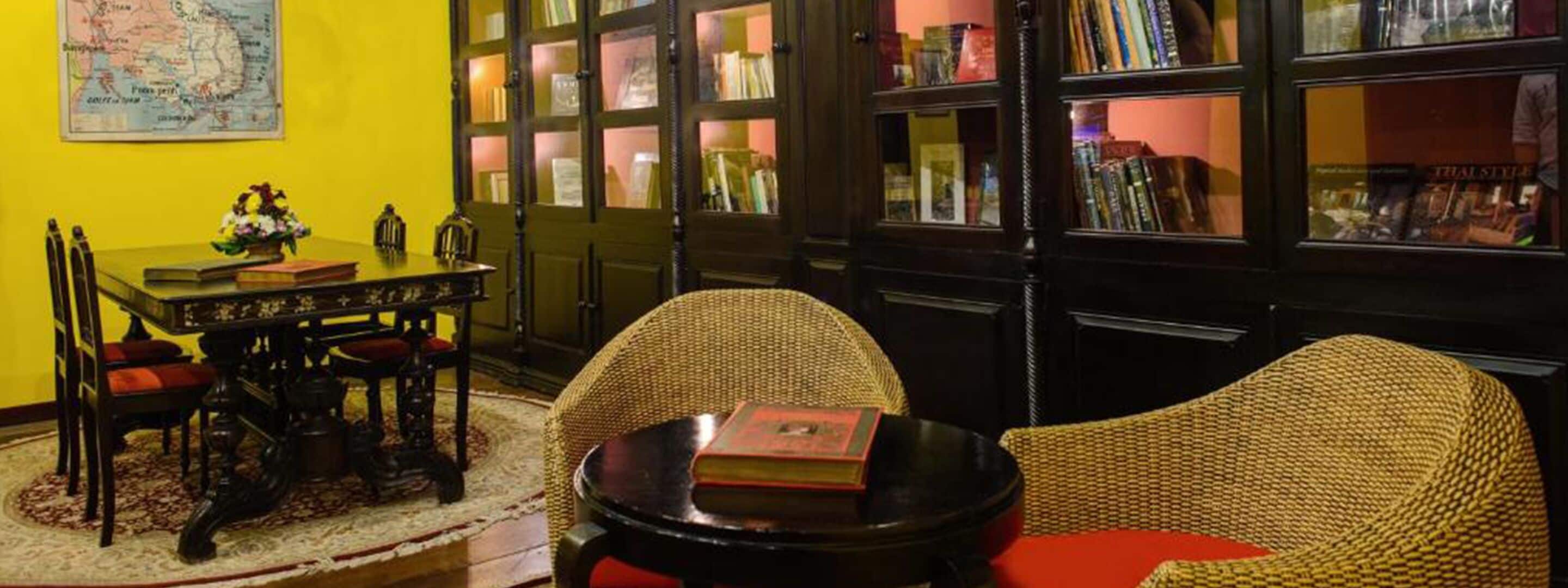 Una habitación con una mesa de comedor, sillas, una estantería y un mapa en la pared.