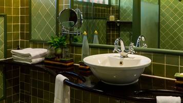 A bathroom with a white sink, green tiled walls, a mirror, and a towel rack.