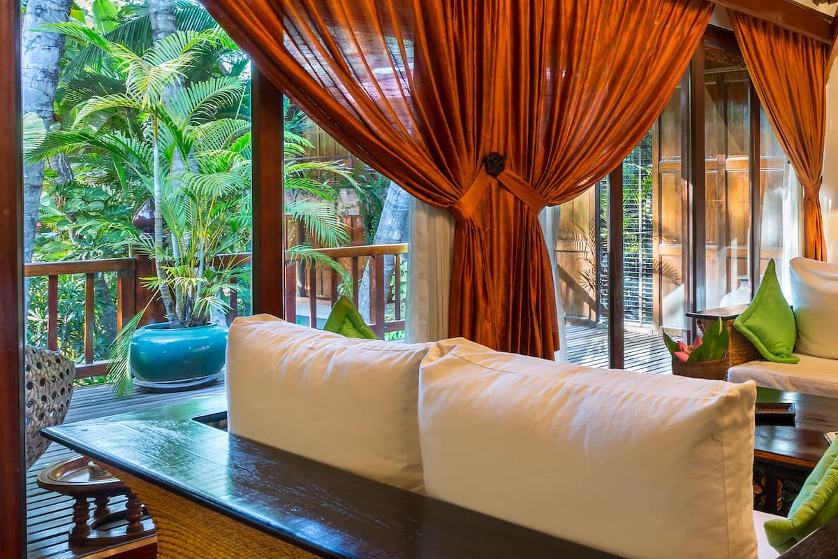A room with a sofa set, a television, and a table with a lamp.