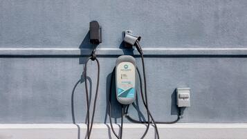 An electric vehicle charging station with a visible solar panel and a Siemens plug.