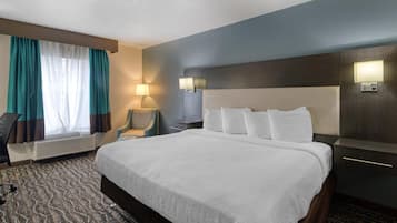 Una habitación de hotel con una cama grande, un escritorio, una silla, una lámpara y una ventana con cortinas.