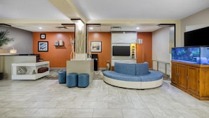 A living room with a curved sofa, a wooden cabinet, and a fish tank. - Best Western Waldo Inn and Suites (Waldo)
