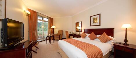 A hotel room with a large bed, a television, a desk, and a chair.