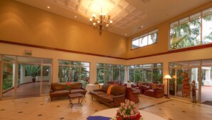 A spacious lobby with multiple seating areas, a chandelier, and large windows offering views of greenery.