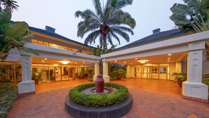 A hotel courtyard with a central water feature, palm trees, and a brick floor.
