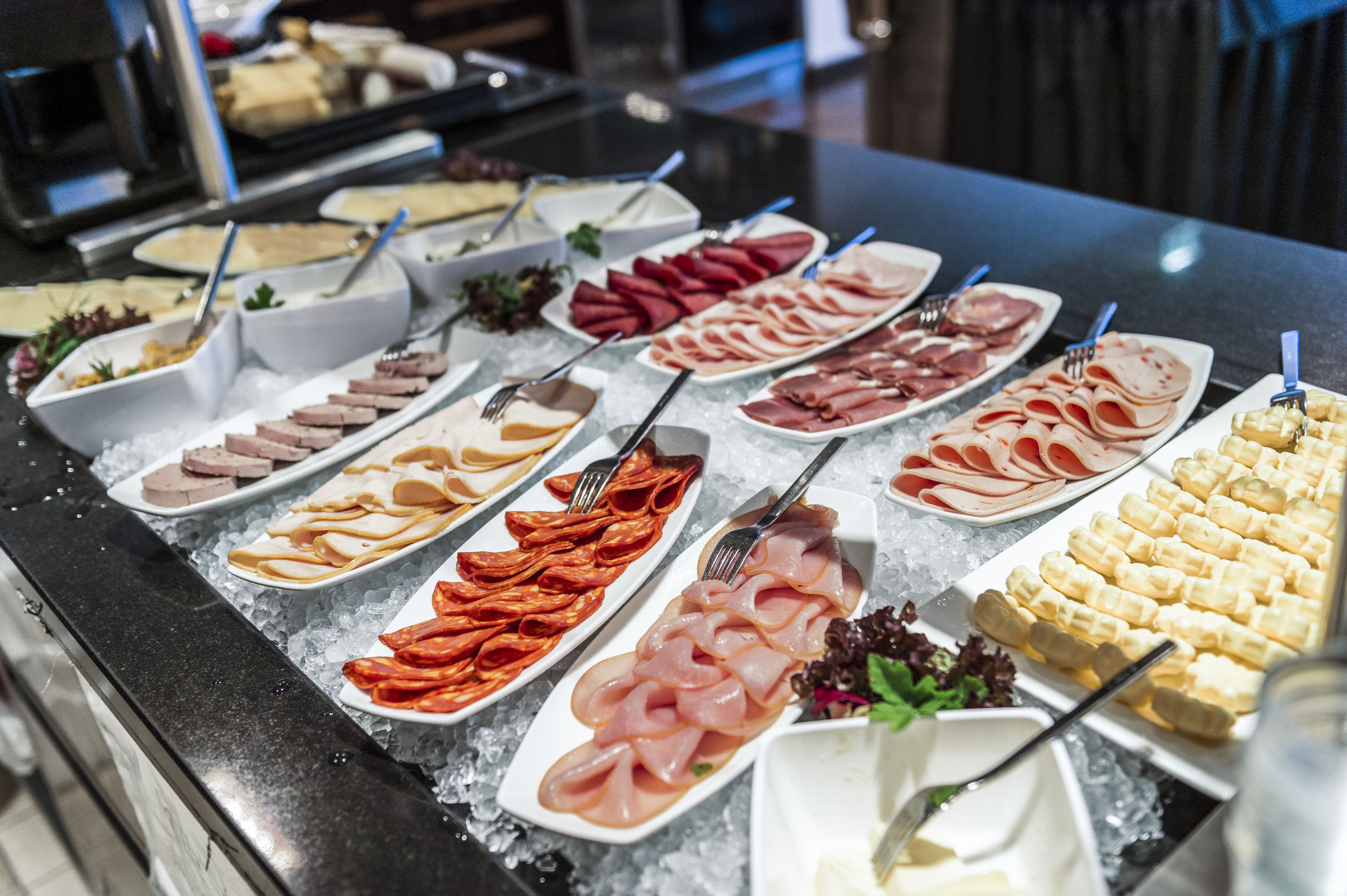 A buffet with various cold cuts, cheeses, and other deli items displayed on ice.