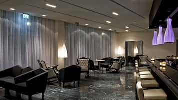Un moderno vestíbulo de hotel con piso de mármol, asientos de cuero e iluminación colgante.