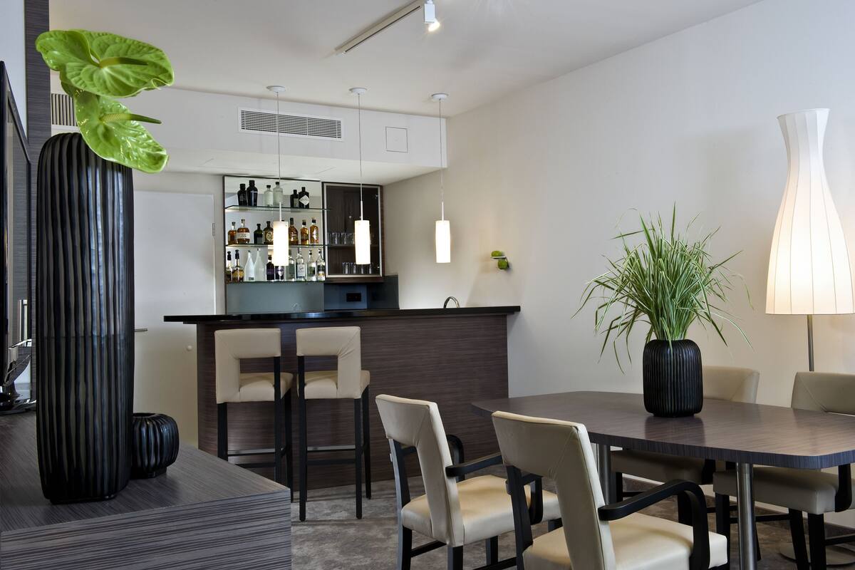 Un comedor moderno con una mesa de madera oscura, sillas color beige y una planta en maceta.
