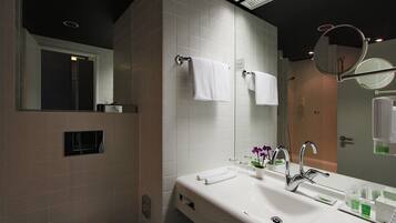 Un baño moderno con un lavamanos blanco, dos espejos y un perchero para toallas.