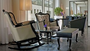 Un moderno vestíbulo de hotel con sillones de cuero, una pequeña mesa con un florero y grandes ventanales que aportan luz natural.