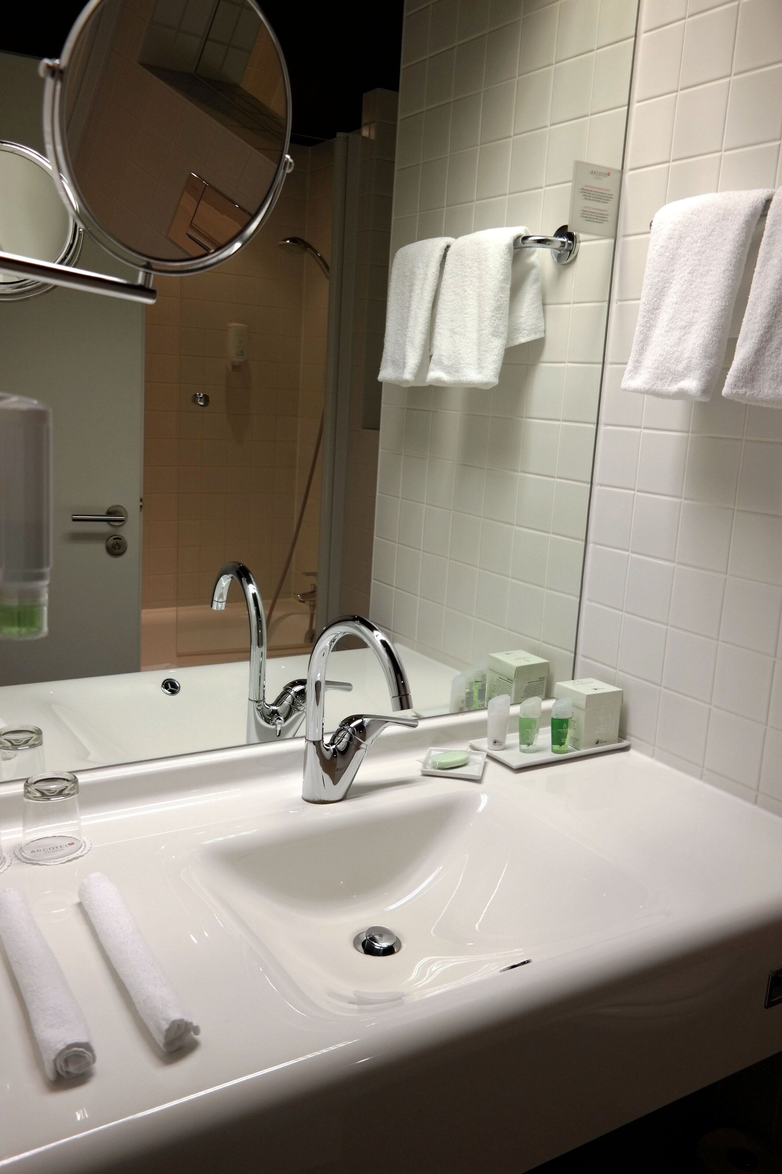 Un baño con un espejo grande, un lavabo y dos toallas colgadas en la pared.