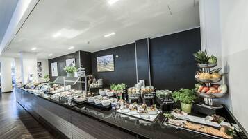 Un espace buffet proposant différents stands de restauration, notamment des options végétaliennes, ainsi qu’un long comptoir avec des places assises.