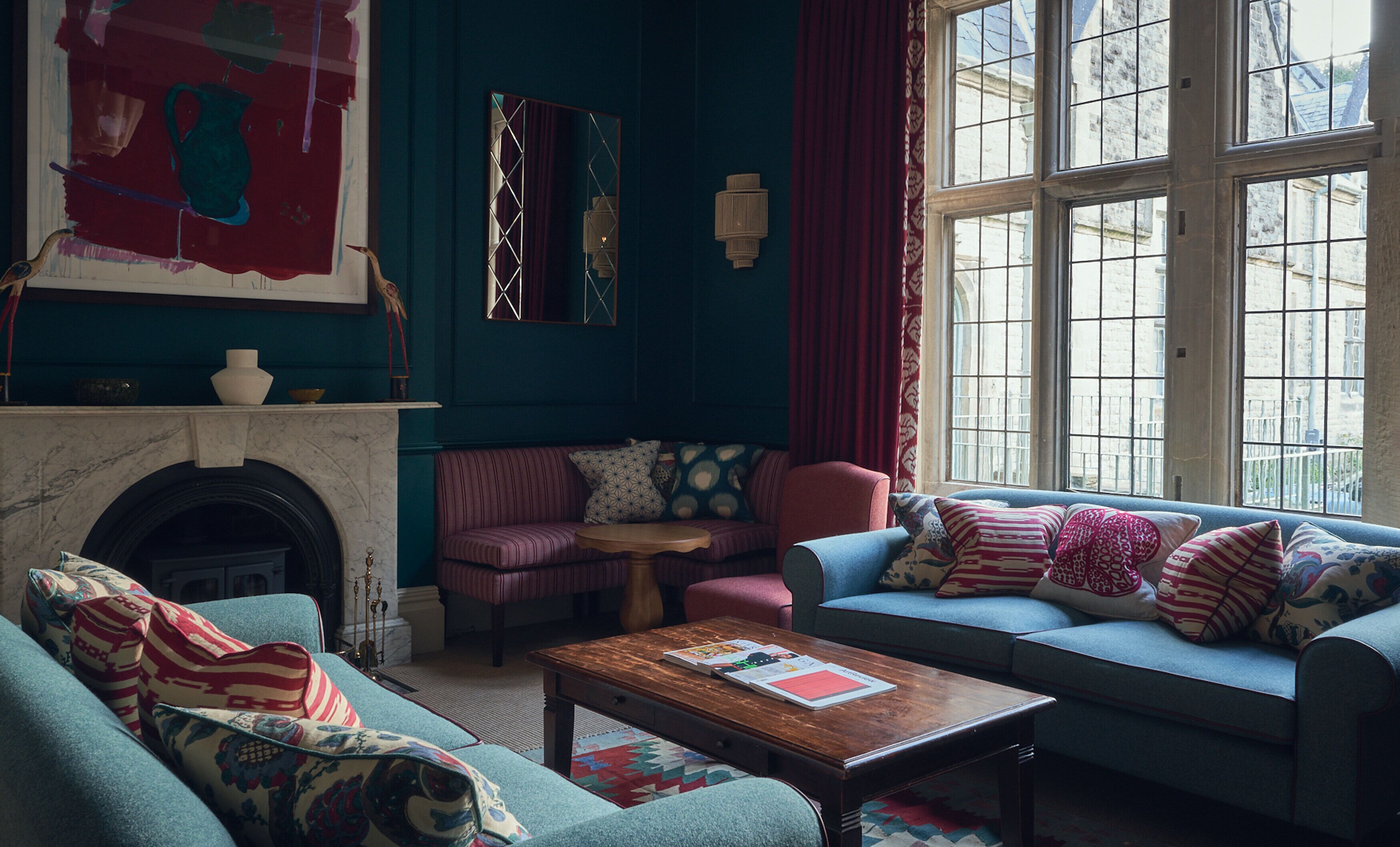 A cozy living room with a fireplace, a blue sofa, a striped armchair, and a coffee table.