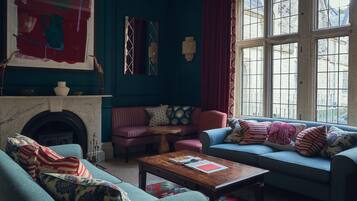 A cozy living room with a fireplace, a blue sofa, a striped armchair, and a coffee table.