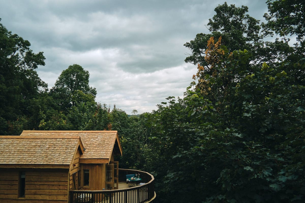 Eine Holzhütte mit Balkon, umgeben von dichtem Wald.
