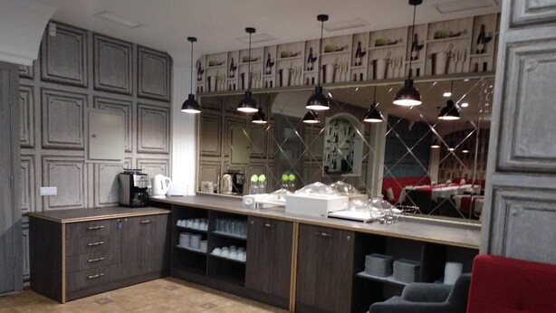 A modern kitchen with dark cabinetry, a central island, pendant lighting, and a red chair. - Villa Natali (Chisinau)