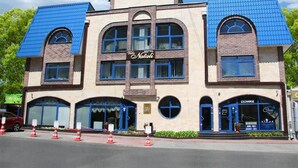 A hotel with a central sign reading "Hotel Nataly," featuring a classic architectural style with blue-tiled roofs and arched windows. - Villa Natali (Chisinau)