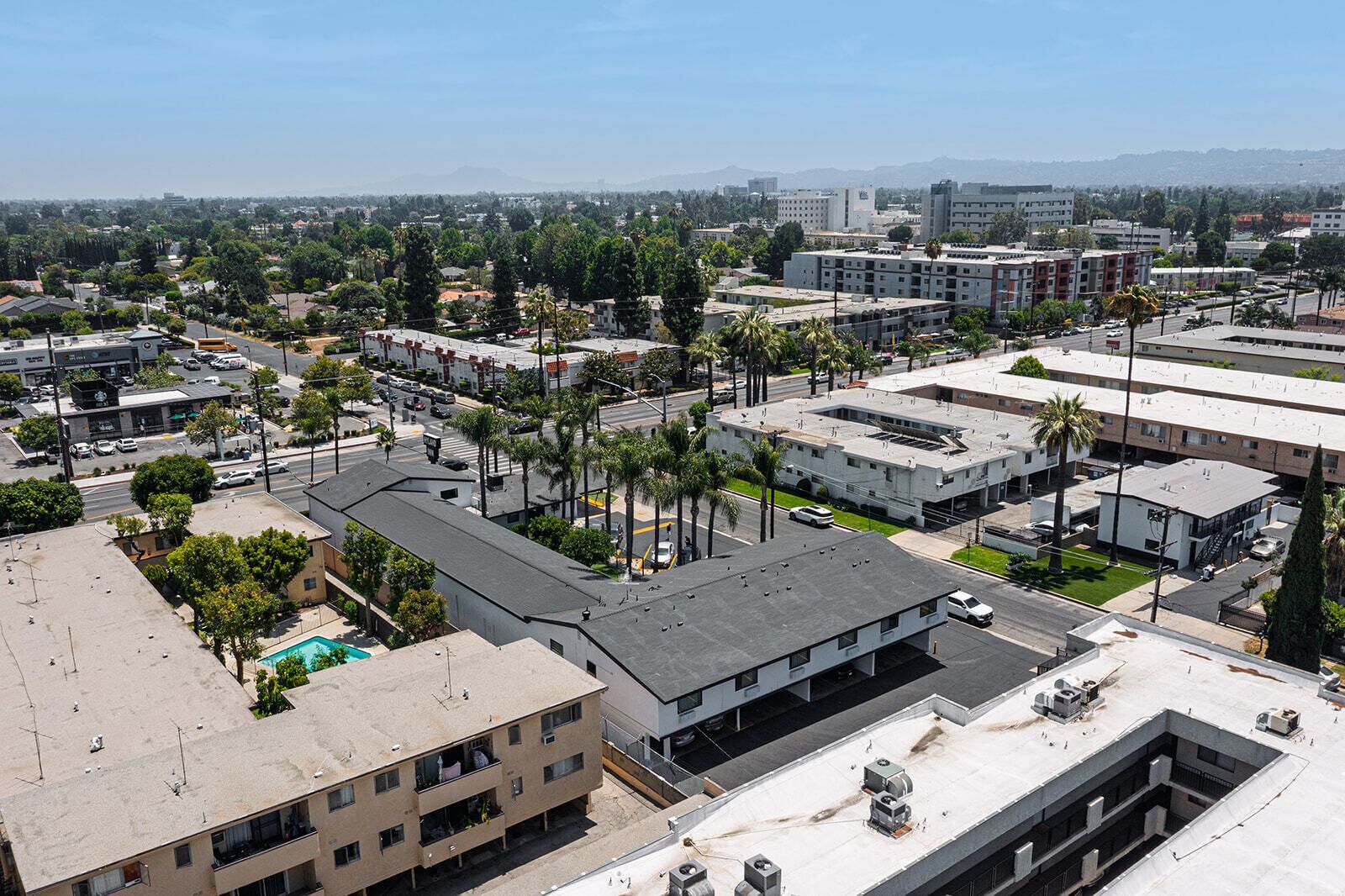 A high-rise building with multiple floors, a rooftop pool, and a parking area.