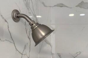 Un cabezal de ducha fijado a la pared, con diseño de mármol.