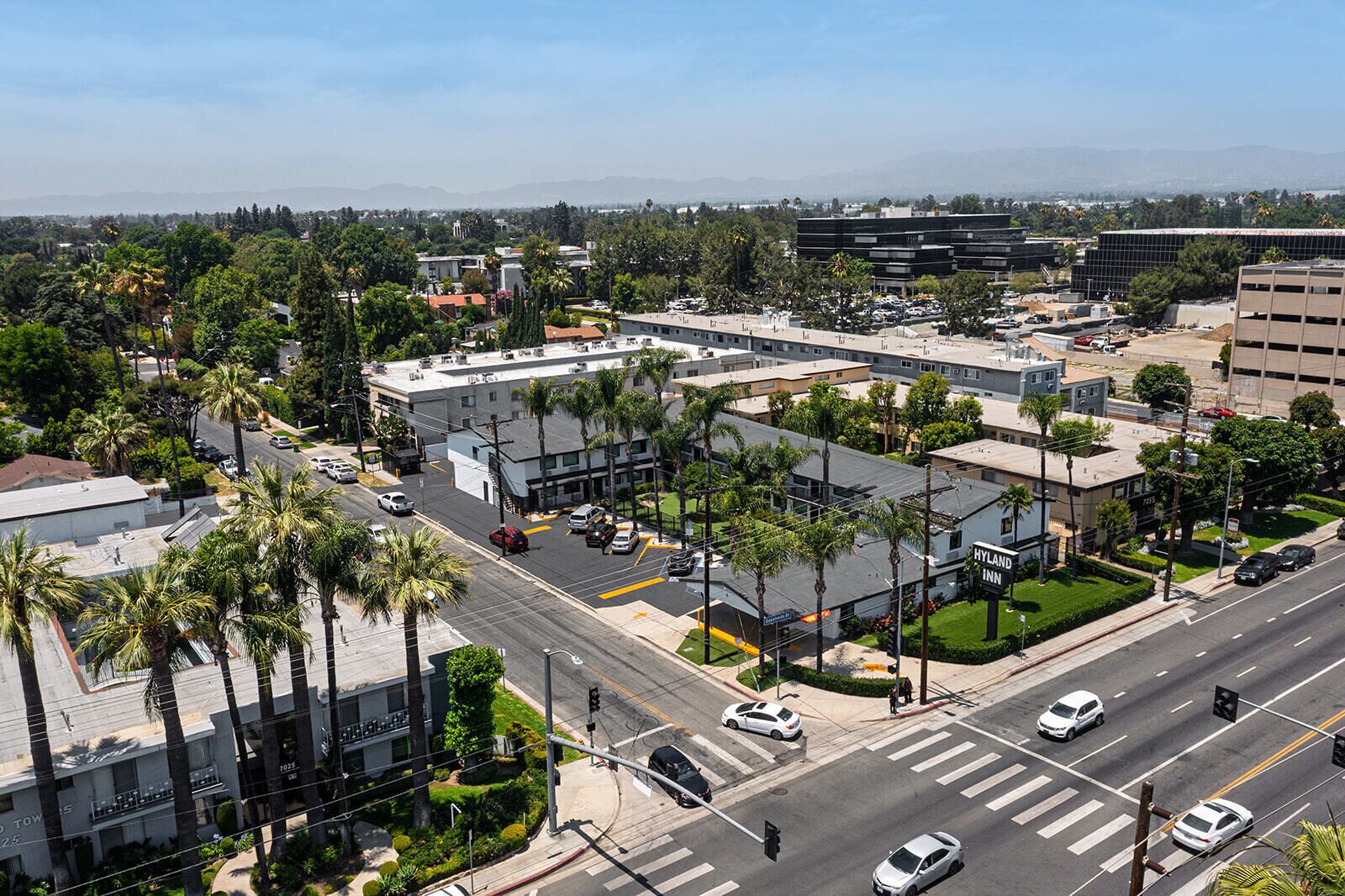 Un hôtel à plusieurs étages doté d’un parking, de palmiers et offrant une vue dégagée sur le paysage urbain environnant.